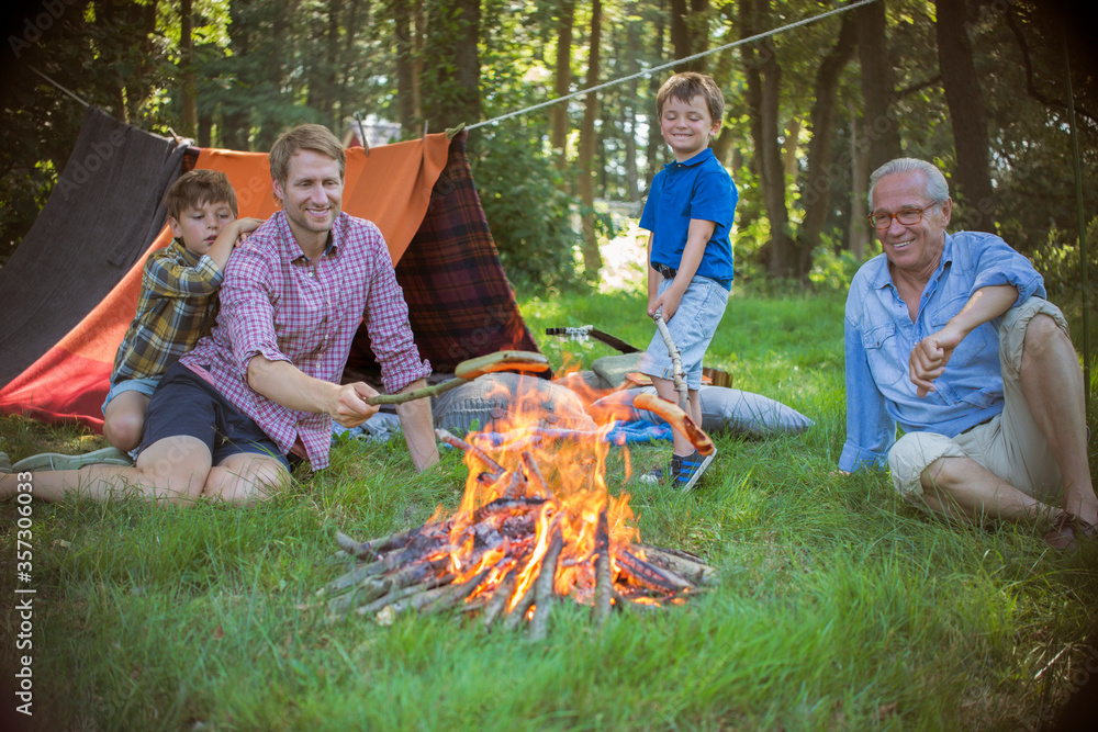 Boy, father and grandfather relaxing near campfire Boy, father and grandfather relaxing near campfire
