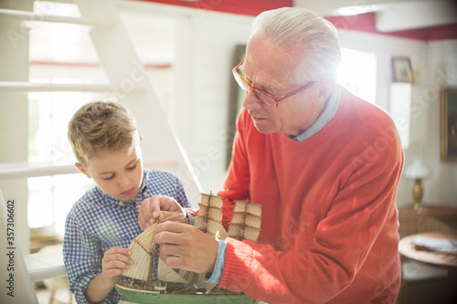 Grandfather and grandson building model sailboat