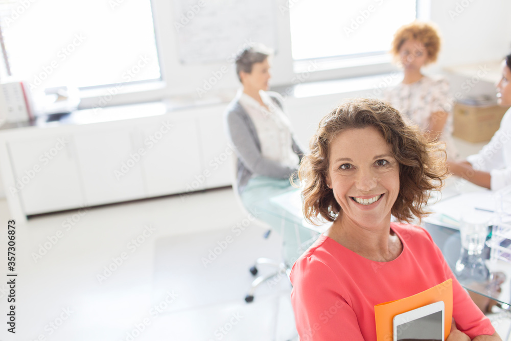 Obraz premium Portrait of smiling businesswoman in office, colleagues in background