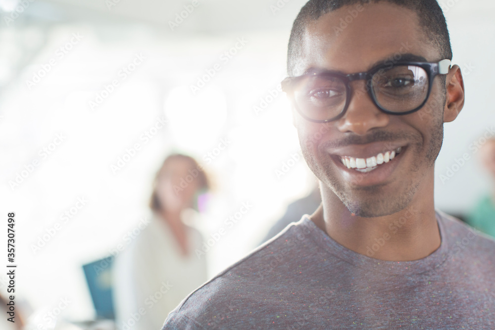 Portrait of young smiling man wearing glasses, woman in background Portrait of young smiling man wearing glasses, woman in background