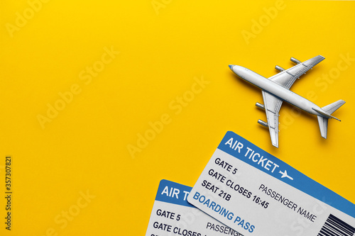 Toy plane with tickets on a yellow background with copy space.