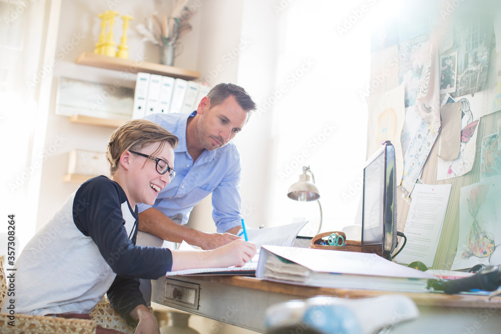 Father helping teenage son doing his homework in room Father helping teenage son doing his homework in room