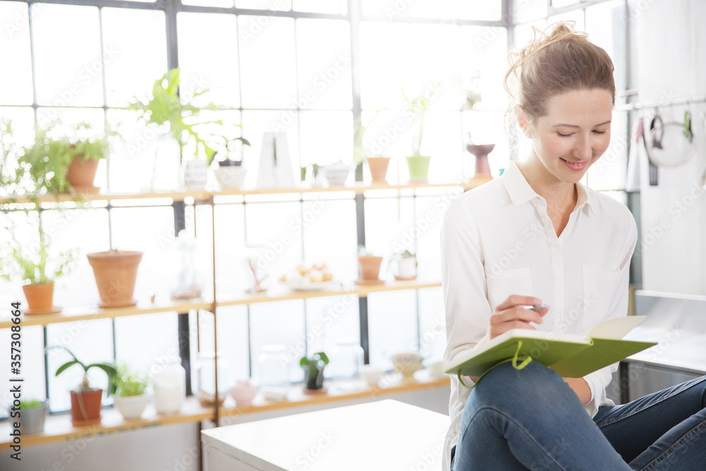 Woman sitting on kitchen counter and writing in her notebook Woman sitting on kitchen counter and writing in her notebook