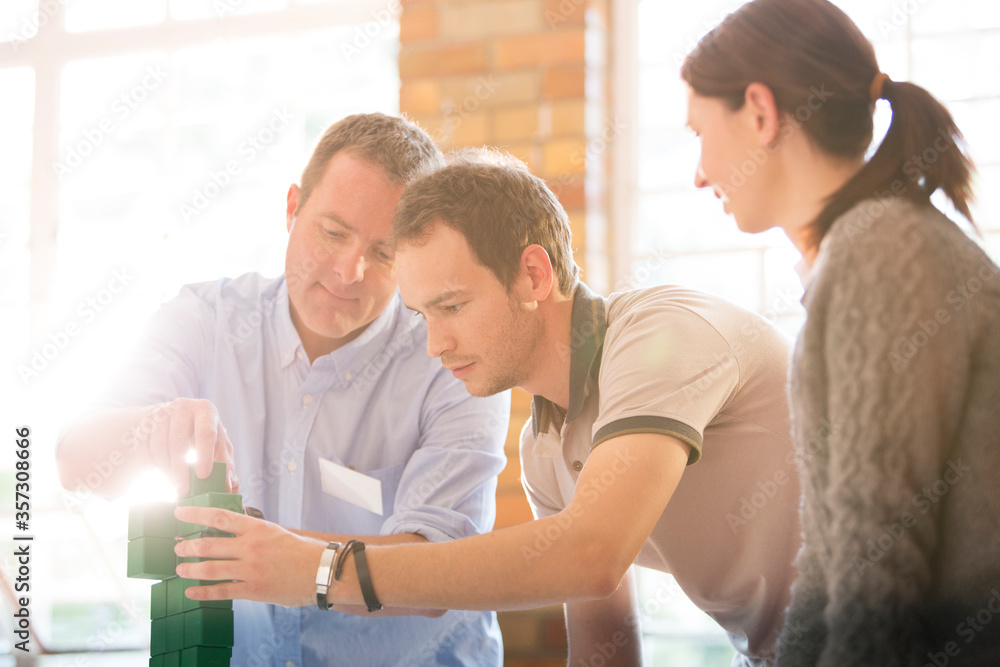 Fototapeta premium Business people stacking green blocks in sunny office