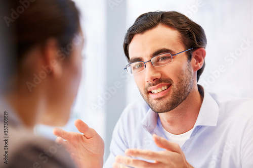 Smiling man in glasses in office with client