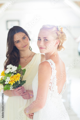 Portrait of bride bridesmaid with bouquet of flowers in domestic room