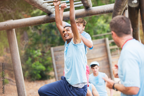 Photography Man crossing monkey bars on boot camp obstacle course