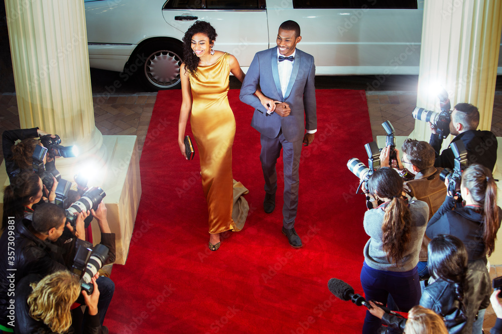 Celebrity couple arriving at red carpet event being photographed by