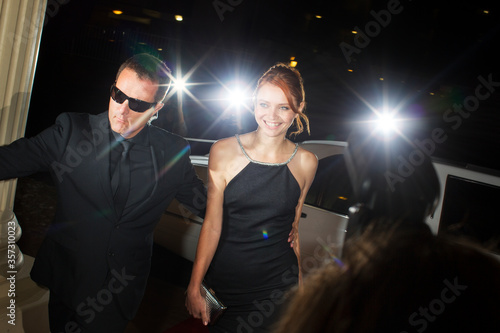 Bodyguard escorting smiling celebrity arriving at event
