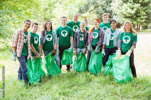 Portrait of smiling environmentalist volunteers picking up trash photo