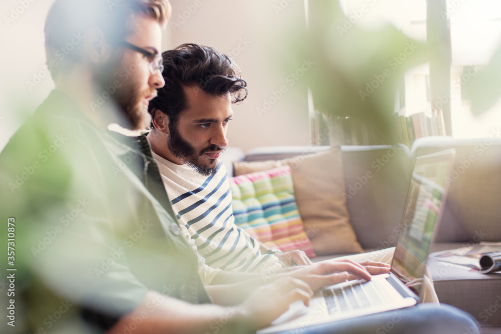 Casual businessmen working at laptop on sofa in office Casual businessmen working at laptop on sofa in office