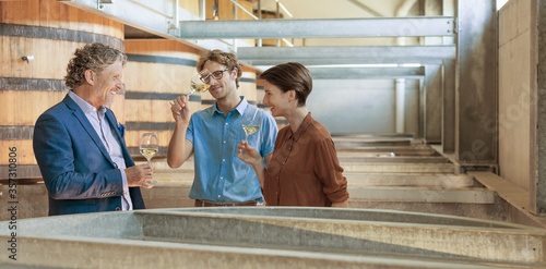 Friends barrel tasting wine in winery cellar
