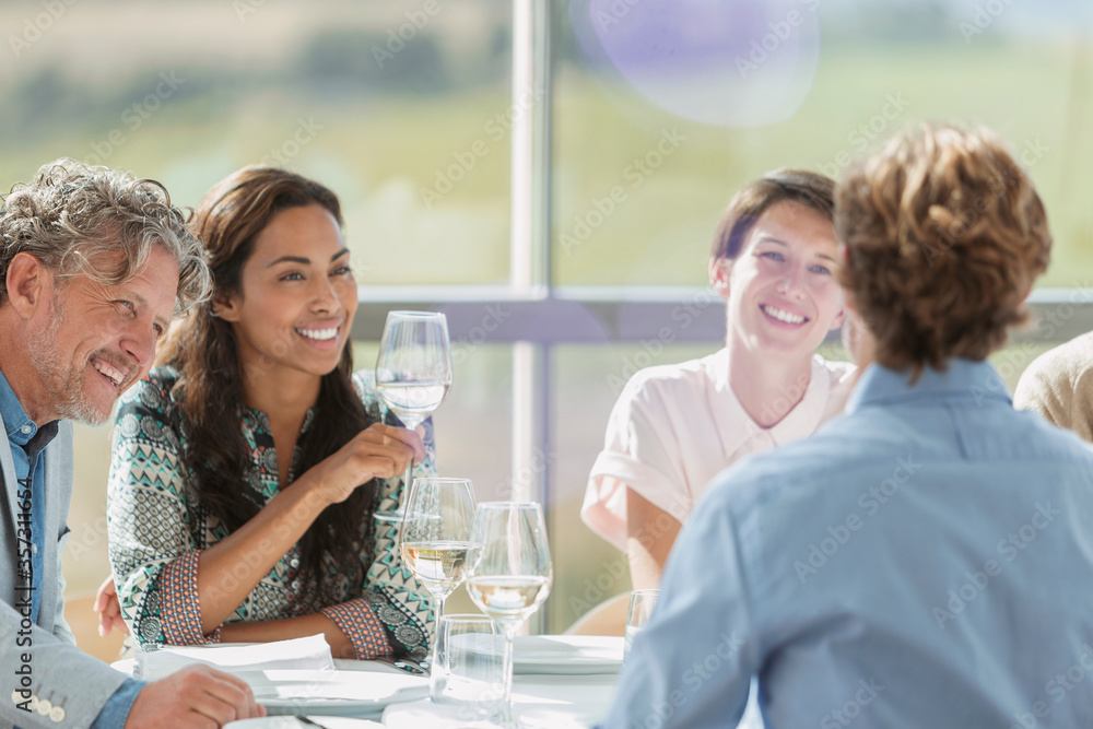 Friends drinking wine and talking at restaurant table Friends drinking wine and talking at restaurant table