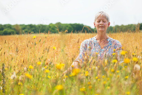 Senior woman meditating in rural field