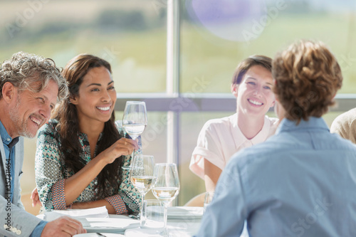 Friends drinking wine and talking at restaurant table