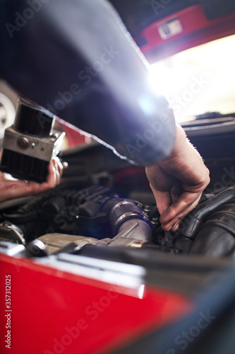 Close up mechanic arm reaching in car engine