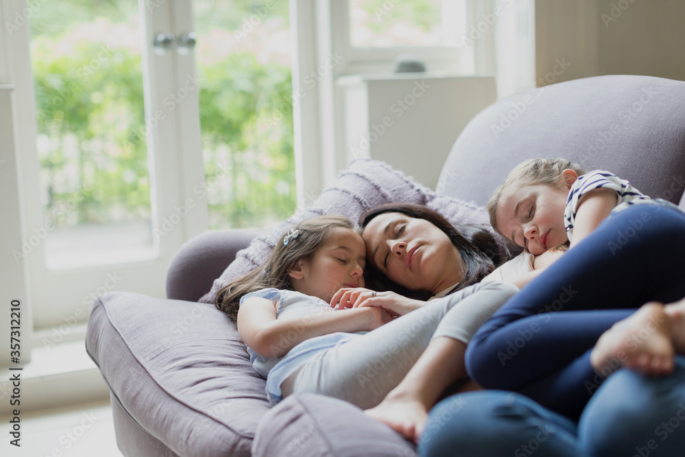 Serene mother and daughters napping on living room sofa Serene mother and daughters napping on living room sofa