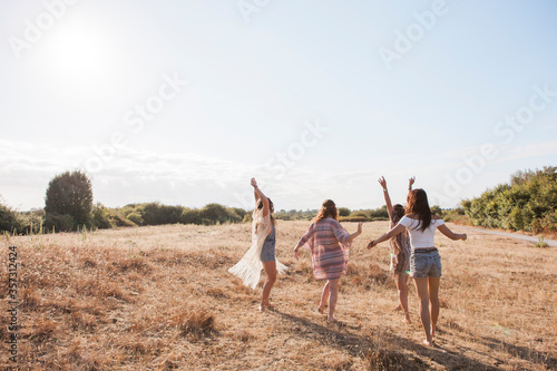Carefree boho women dancing in sunny rural field