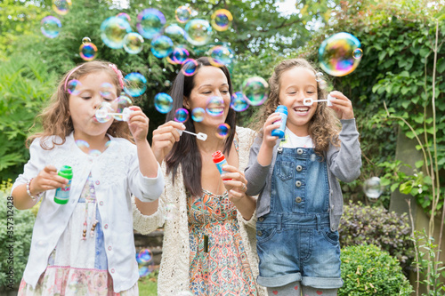 Mother and daughters blowing bubbles in backyard