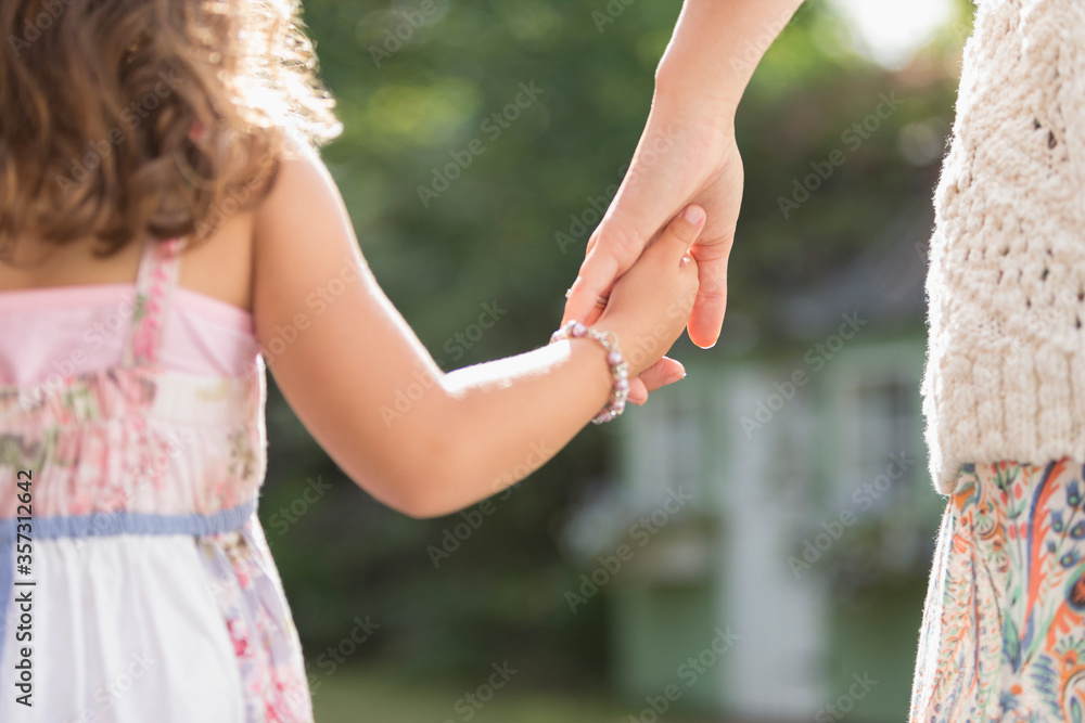 Close up rear view mother and daughter holding hands Close up rear view mother and daughter holding hands