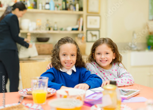 Portrait smiling sisters at breakfast table