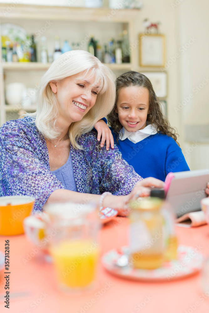 Grandmother and granddaughter using digital tablet at breakfast table Grandmother and granddaughter using digital tablet at breakfast table