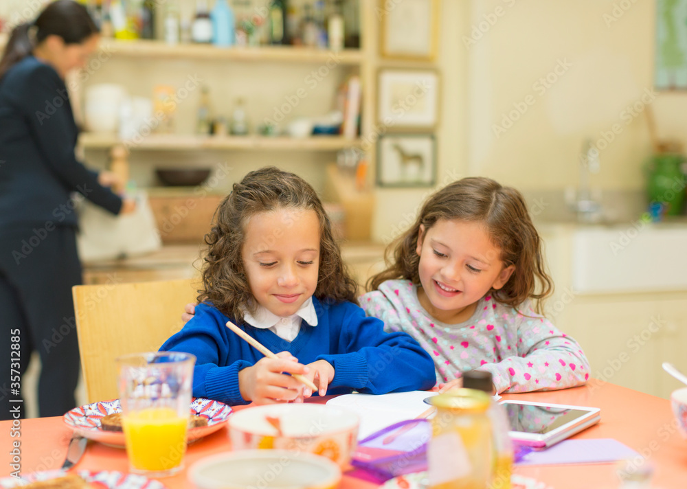 Fototapeta premium Girls doing homework at breakfast table