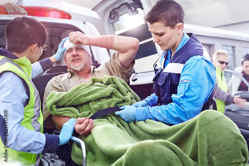 Rescue workers tending to car accident victim on stretcher at back of ambulance