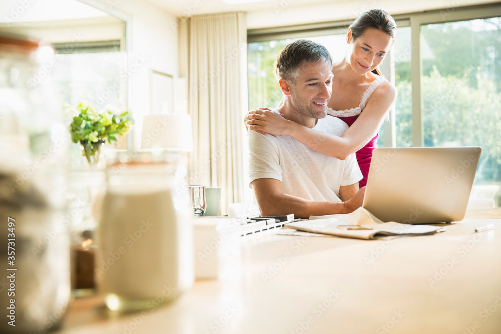 Couple using laptop in morning kitchen Couple using laptop in morning kitchen
