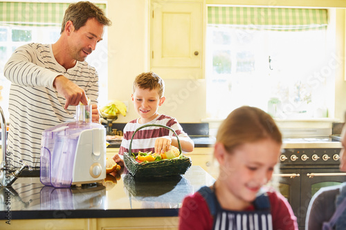 Fotografia Father and son juicing vegetables in kitchen