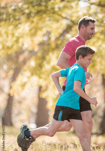 Fototapeta Naklejka Na Ścianę i Meble -  Father and son jogging in park