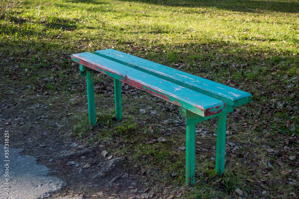 A bench without a backrest stands near the track. Painted bench, paint peeled off