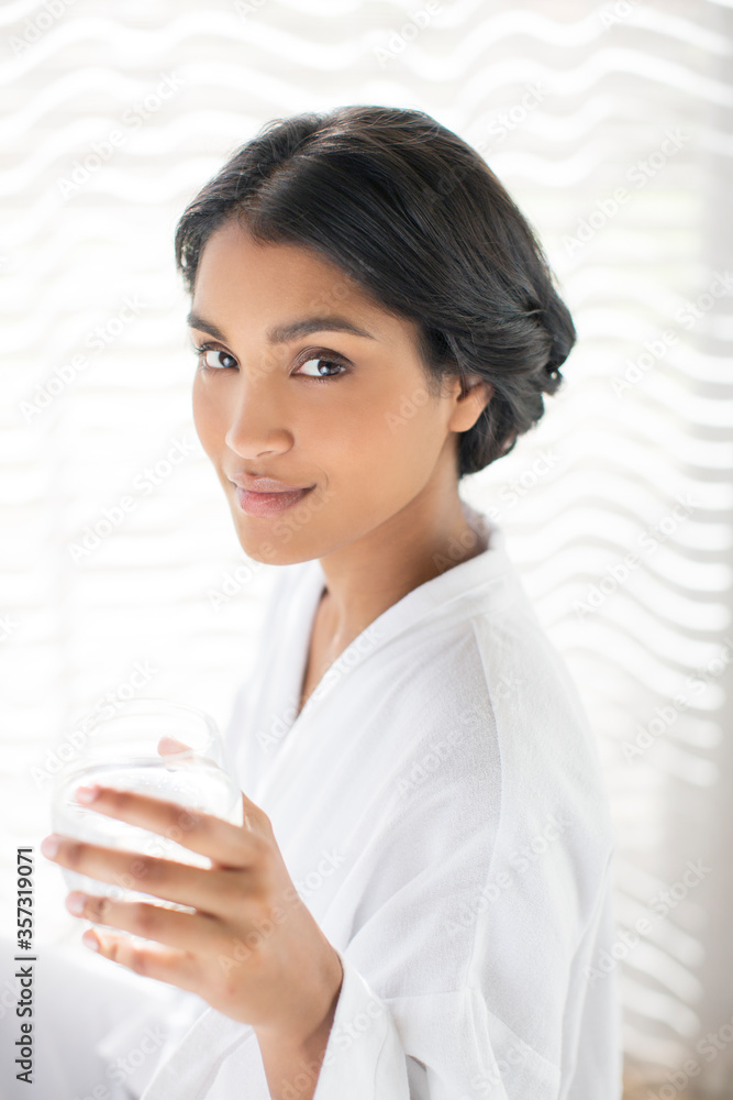 Portrait confident woman in bathrobe drinking water Portrait confident woman in bathrobe drinking water