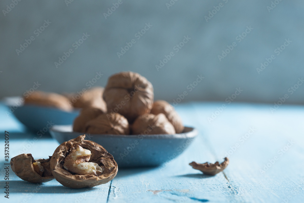 cracked walnut in front of a walnut bowl shot on blue wood cracked walnut in front of a walnut bowl shot on blue wood