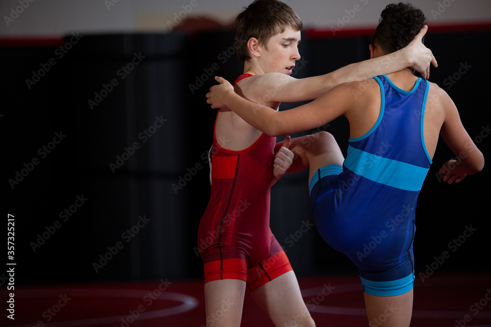 Wrestlers in red and blue singlets practicing on a red mat. Wrestlers in red and blue singlets practicing on a red mat.