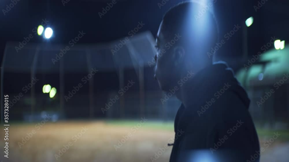 African American Teen Walks on Baseball Field at Night, Profile Medium African American Teen Walks on Baseball Field at Night, Profile Medium