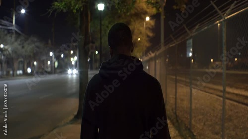 African American Teen Walks Down Street at Night, Behind Medium