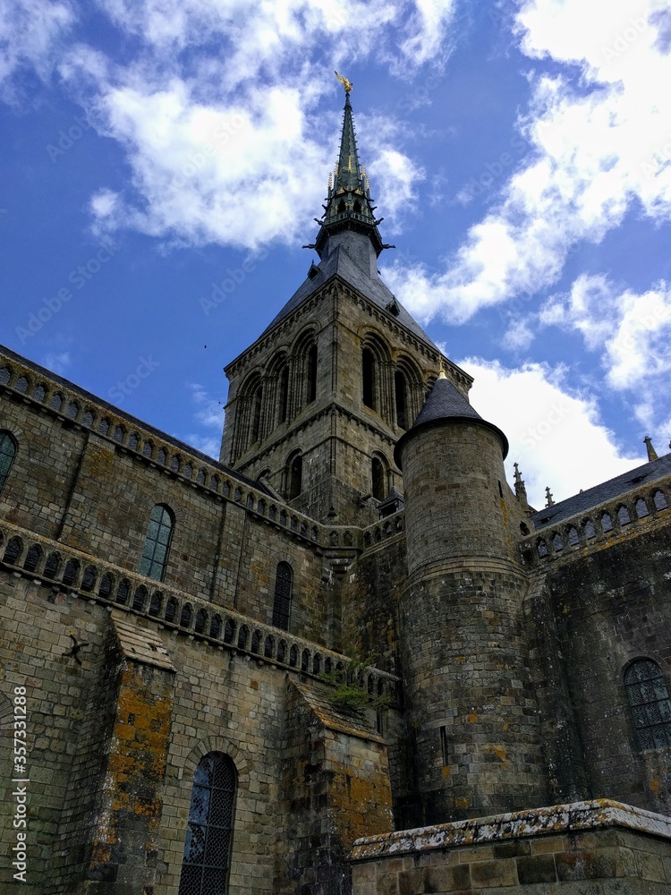 View from inside Mont St. Michel, looking up at golden spire in Normandy France - a top tourist destination