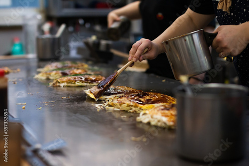 Tableau sur toile Making a Hiroshima style layered pancake, Okonomiyaki on a hot pan