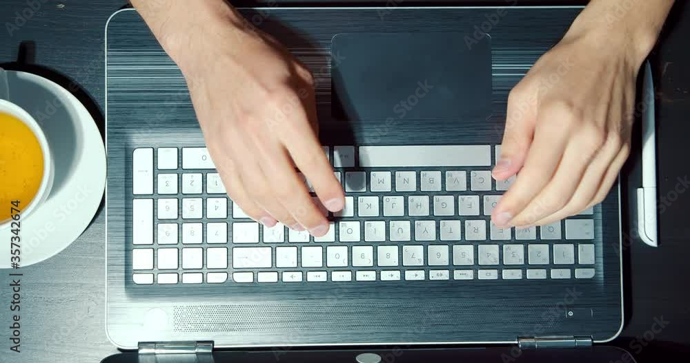 Close up of male hands typing on laptop keyboard at workplace. Top view Close up of male hands typing on laptop keyboard at workplace. Top view