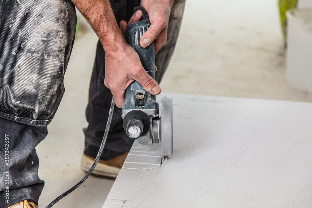 Der Fliesenleger arbeitet im Badezimmer eines modernen Hauses. Schneiden von fliesen mit einem winkelschleifer. Der Fliesenleger arbeitet im Badezimmer eines modernen Hauses. Schneiden von fliesen mit einem winkelschleifer.