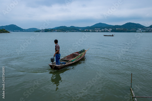 The old man rowed a wooden boat in the lake. © may