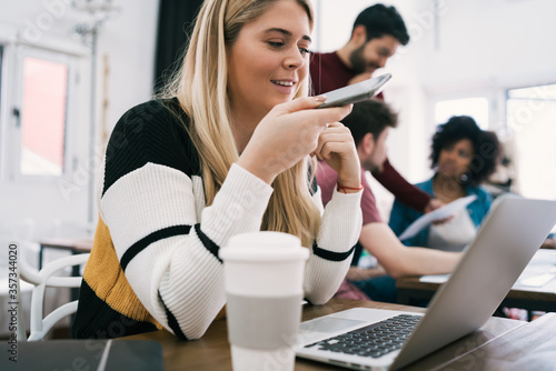 Young business woman sending a voice message.