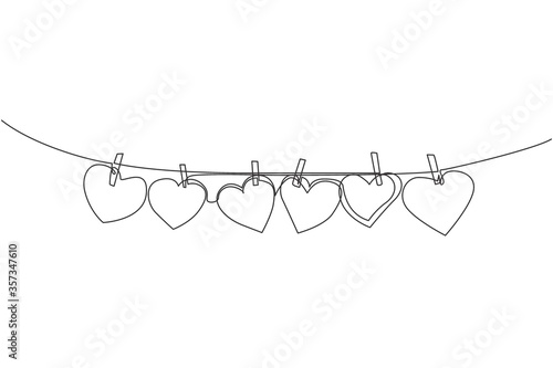 One continuous line drawing of cute heart shape paper hanged on the rope with clothesline. Romantic marriage greeting card concept. Trendy single line draw design graphic vector illustration
