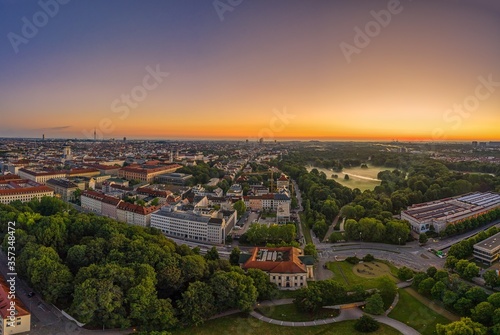 Wide view over Munich at the morning, where the popular green park called Englischer Garten is covered by fog. Panoramic sunrise view from a drone.