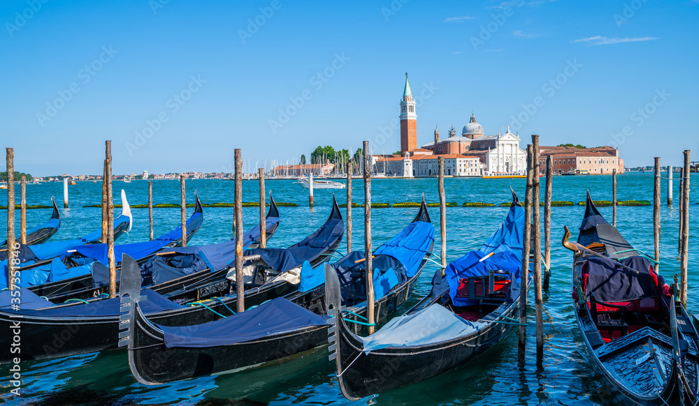 Gondolas moored by Saint Mark square with San Giorgio di Maggiore church in the background in Venice, Italy. Architecture and landmarks of Venice.