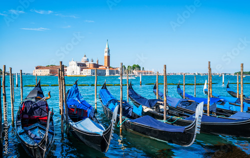 Gondolas moored by Saint Mark square with San Giorgio di Maggiore church in the background in Venice, Italy. Architecture and landmarks of Venice.