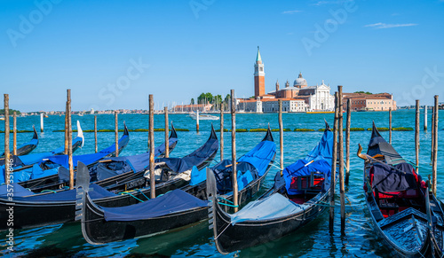 Gondolas moored by Saint Mark square with San Giorgio di Maggiore church in the background in Venice, Italy. Architecture and landmarks of Venice. © eskstock