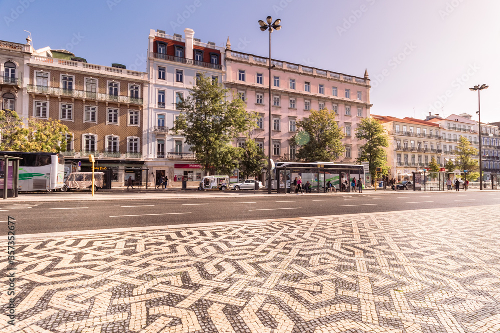 Lisbon / Portugal - 11 08 2018 - City street covered with road tile in Sunny Weather with Portugal Buildings and architecture on the background