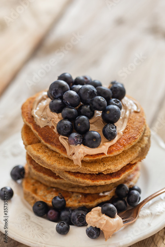 Stack of oatmeal pancakes topped with hazelnut paste and blueber